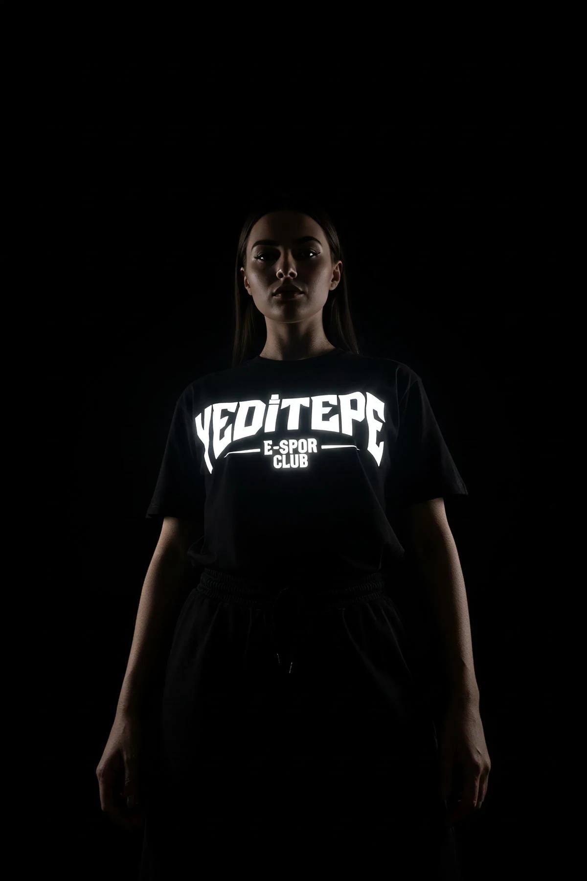 black crop t-shirt with retroreflective print seen from front in low-light setting