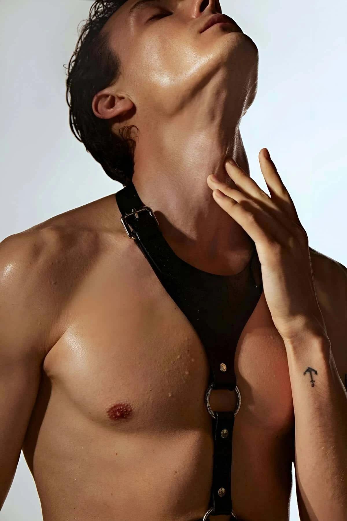 Black faux leather adjustable O-ring chest harness worn on male torso showing silver O-ring junction and narrow straps