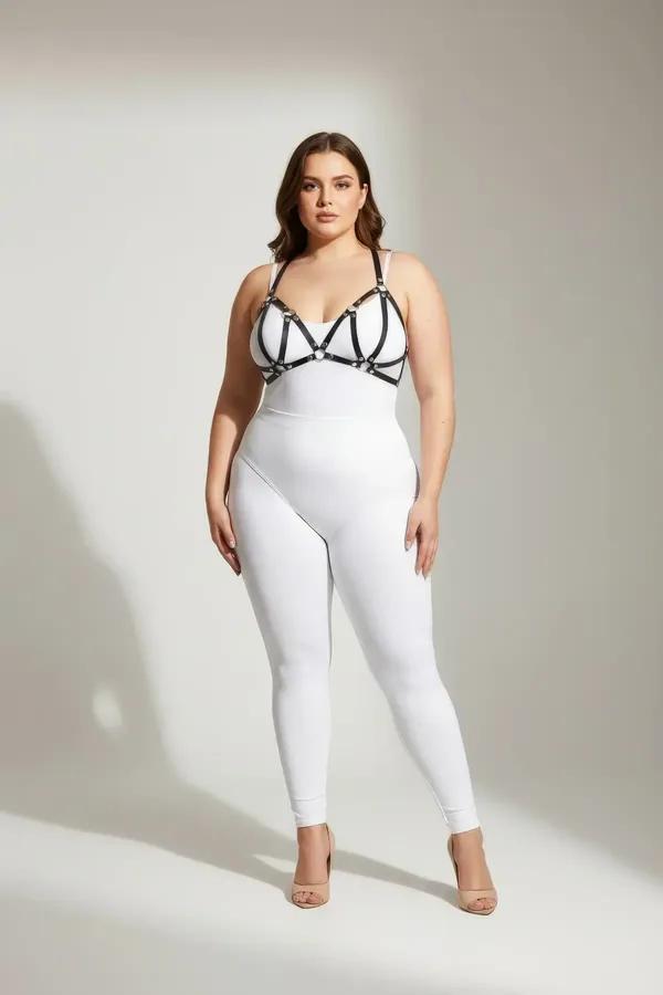Black faux leather strappy chest harness with silver O-ring hardware worn over white top, cage-bra strap configuration