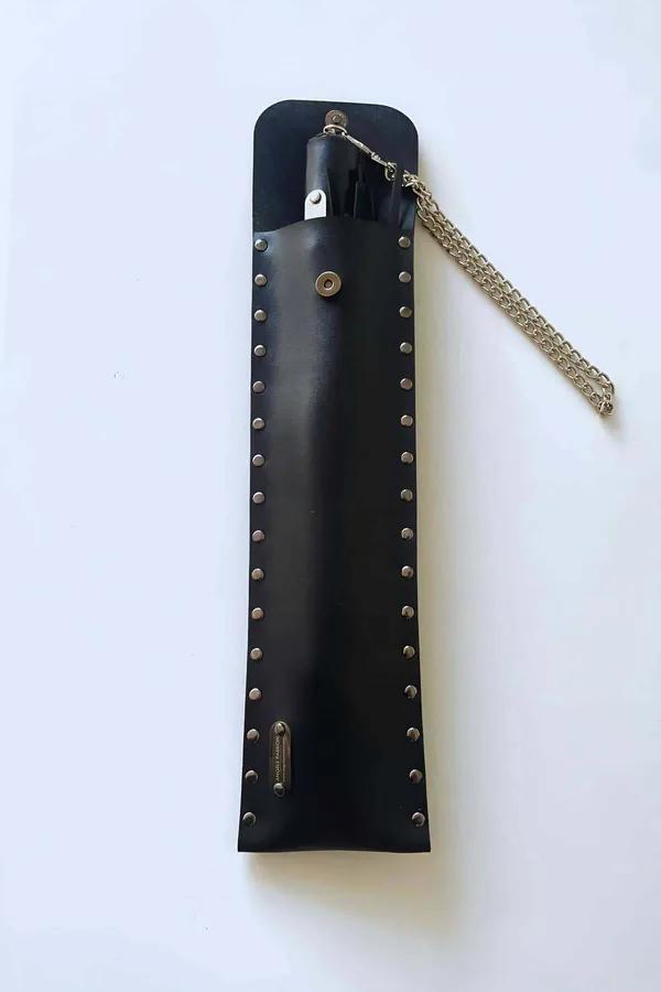 Black studded vegan leather cane in matching snap-close pouch with detachable silver-tone chain wrist strap laid flat
