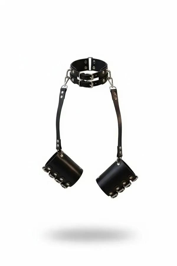 Black faux leather double buckle collar with silver D-rings connected by straps to two wide wrist cuffs against white backgro