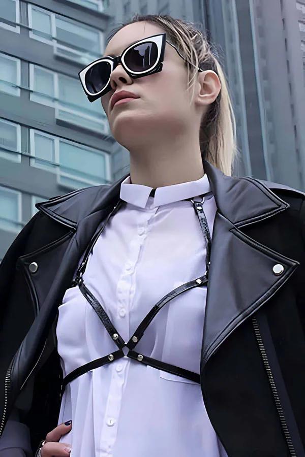 black crocodile-embossed faux leather chest harness with silver O-ring buckle geometric strap over white shirt