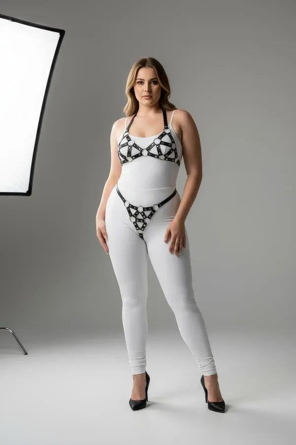 Black faux leather harness bra and garter belt set with silver O-rings worn over white bodysuit and leggings