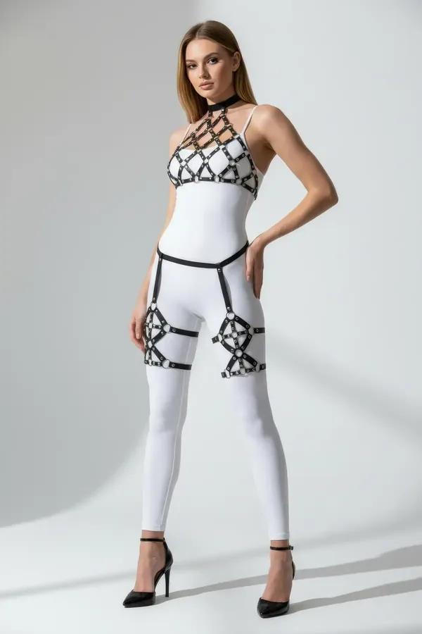 Black faux leather caged bodice harness set with gold O-rings at chest and silver cage thigh pieces worn over white bodysuit