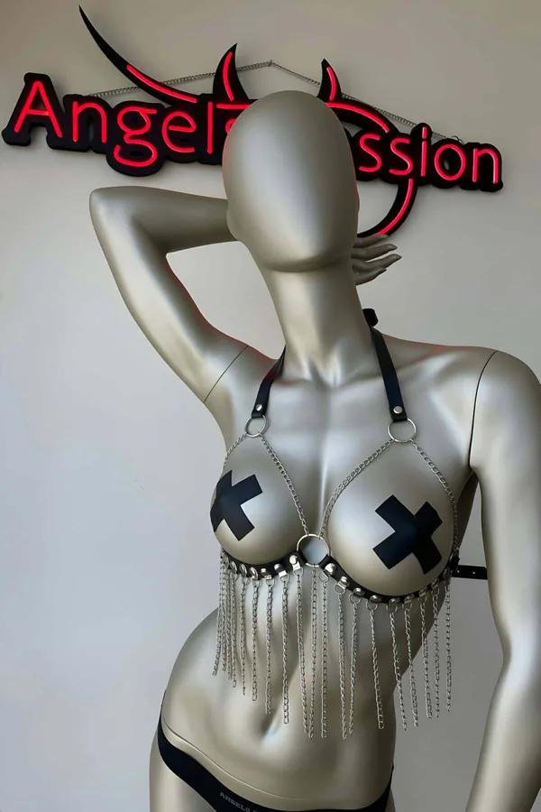 Black faux leather bra harness with silver fringe chains, flat-head studs, center O-ring, and halter neck strap on mannequin