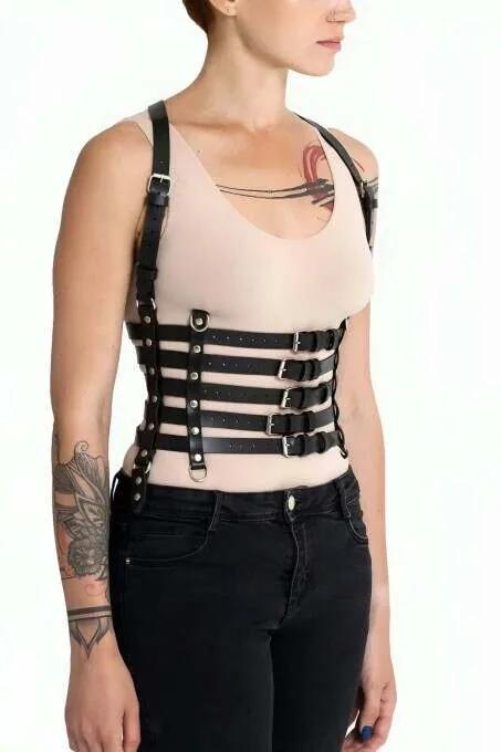 black faux leather underbust corset harness with five horizontal straps and silver buckles worn over beige tank top