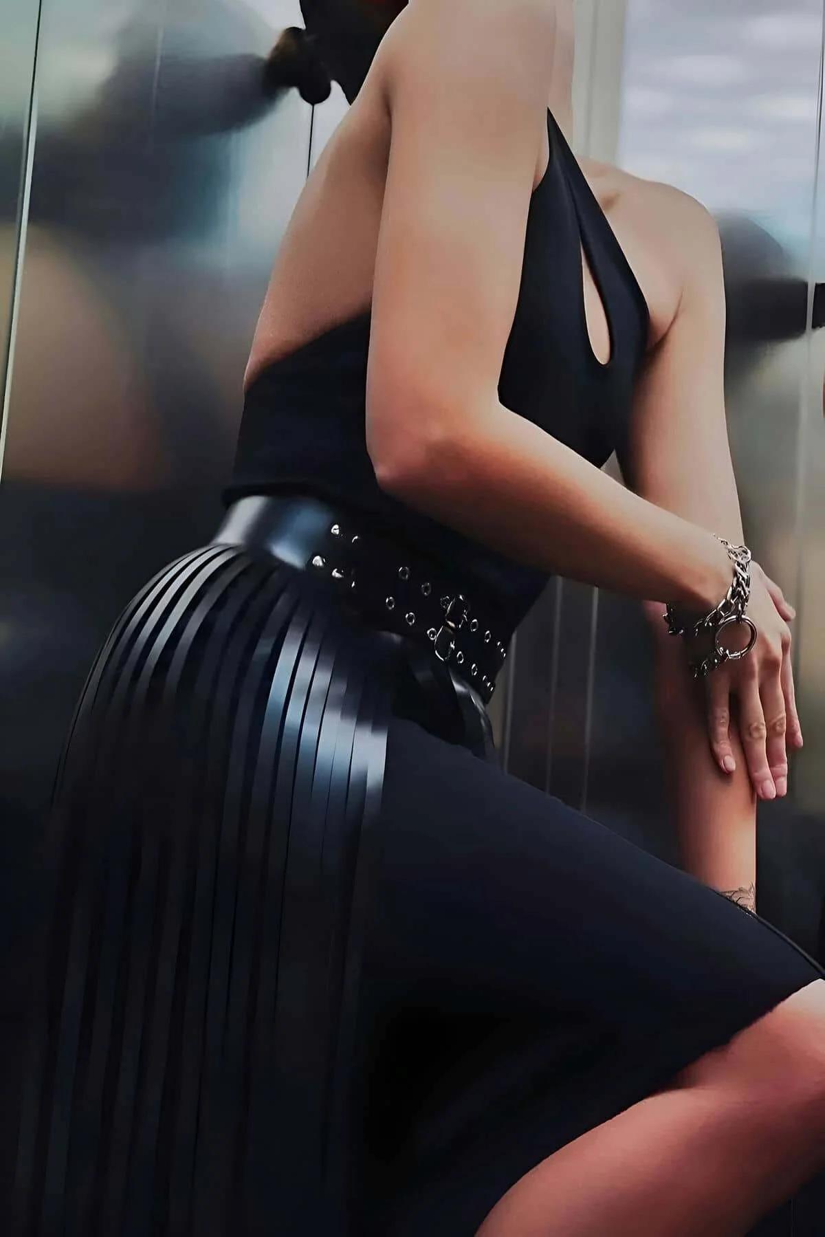 Double-row silver eyelet studded belt on black faux leather midi skirt waistband detail
