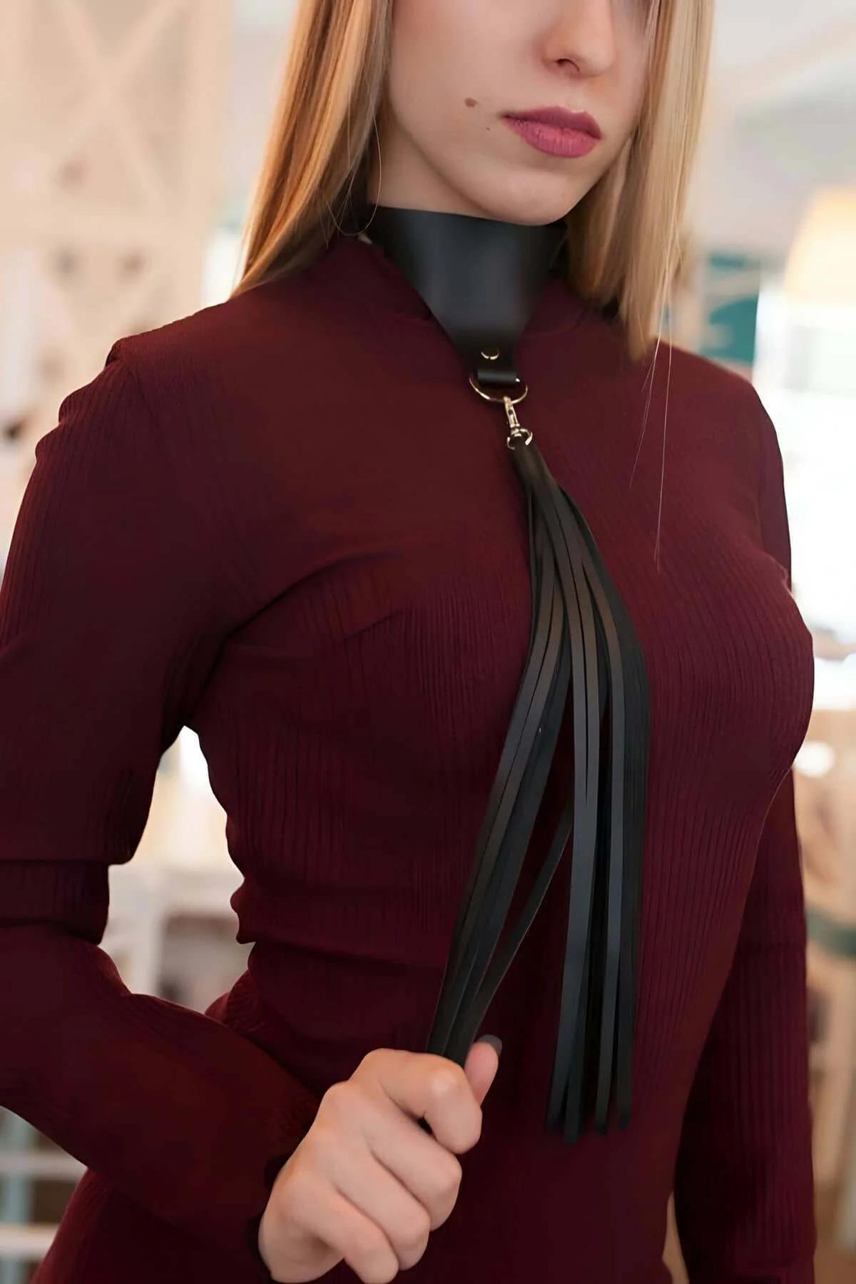Close-up of black PU leather choker band with gold D-ring and long fringed tassel detail