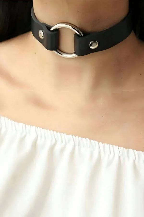 Black faux leather O-ring choker with silver dome rivets and centered silver ring on model neck