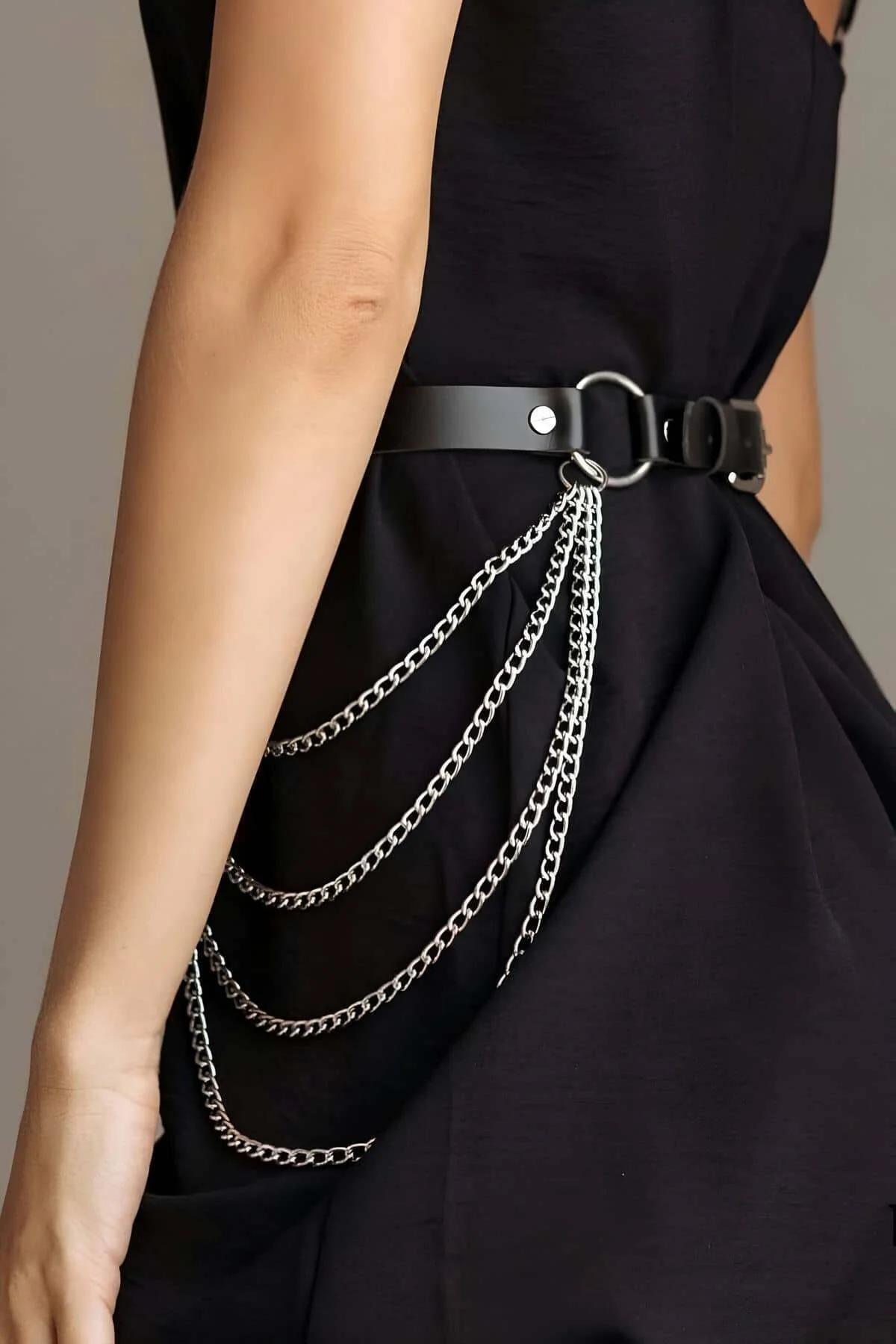 Close-up of silver O-rings and multi-row curb-link chains on black faux leather belt harness