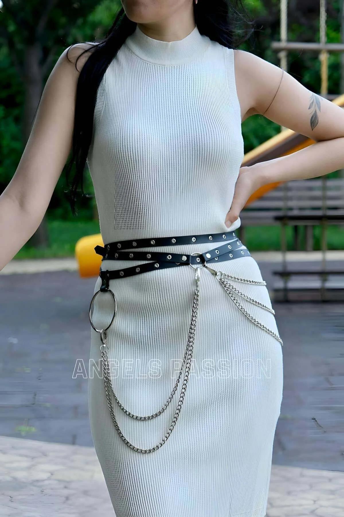 Black studded faux leather belt with layered chains styled at natural waist over dress