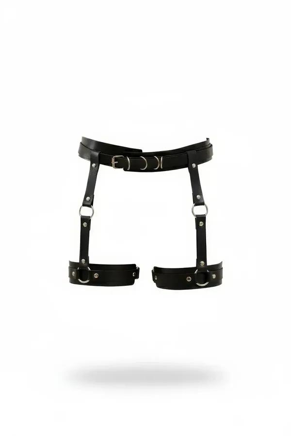 Black faux leather garter harness with dual thigh bands, silver O-rings, rivets, and front pin-buckle waist band on white bac