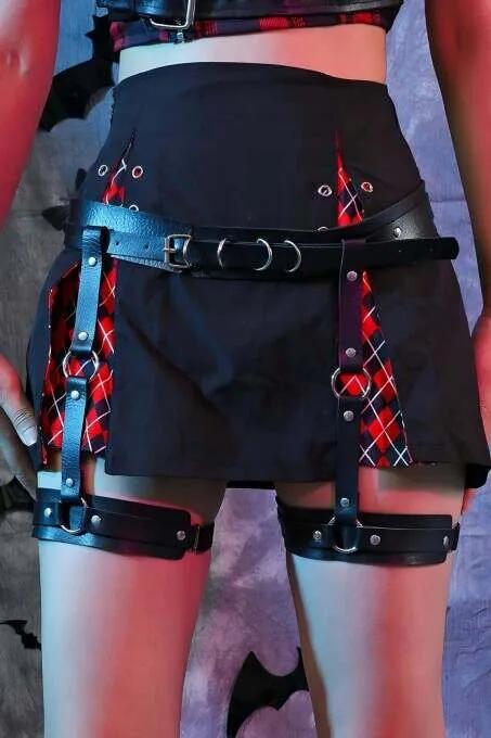 Black faux leather thigh and waist garter harness with silver D-ring buckles worn over a black mini skirt