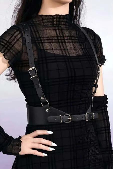 Black faux leather body harness with slim chest straps and wide dual-buckle waist belt on model