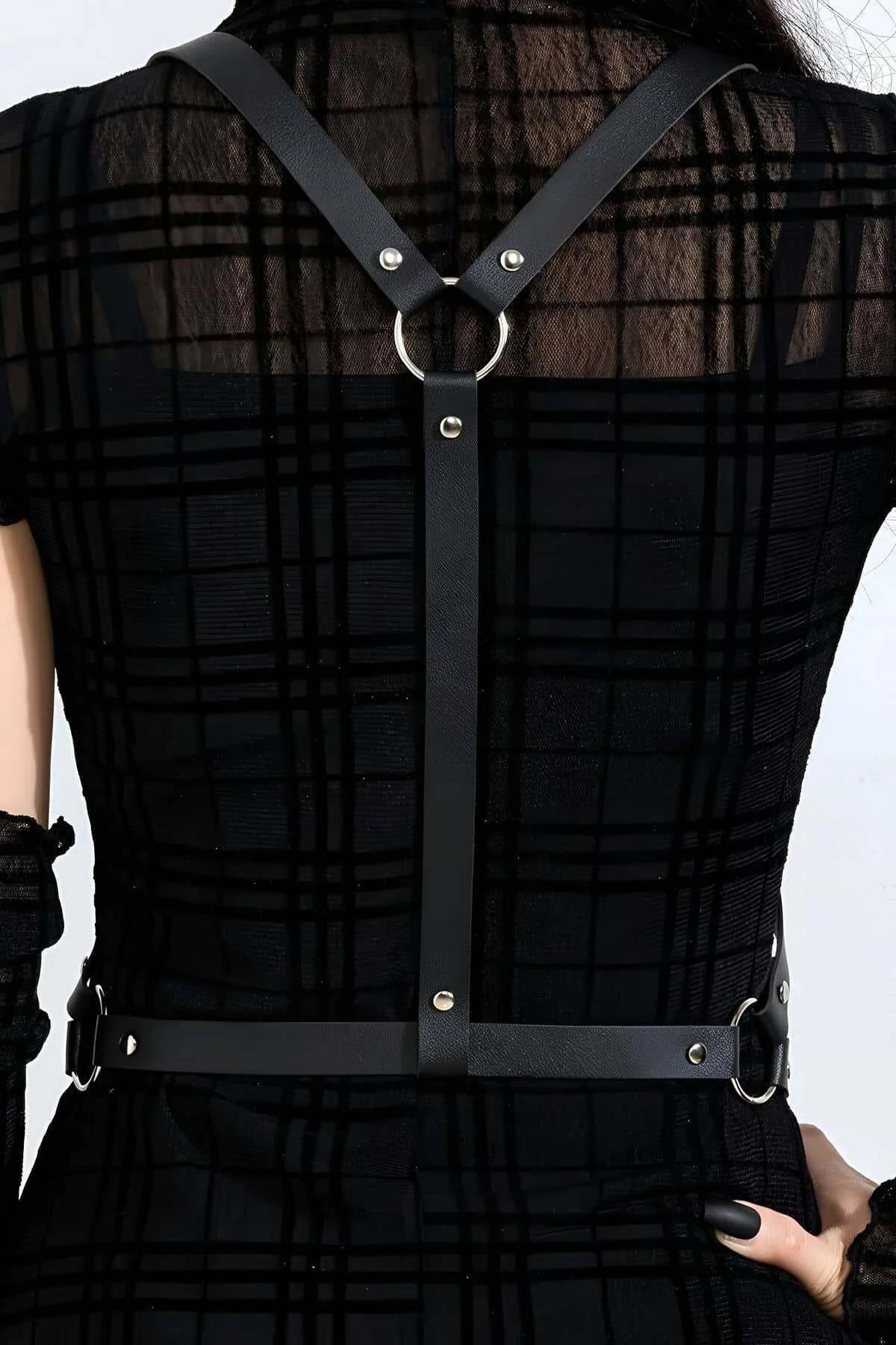 back view of black faux leather diagonal chest harness strap over fitted black top