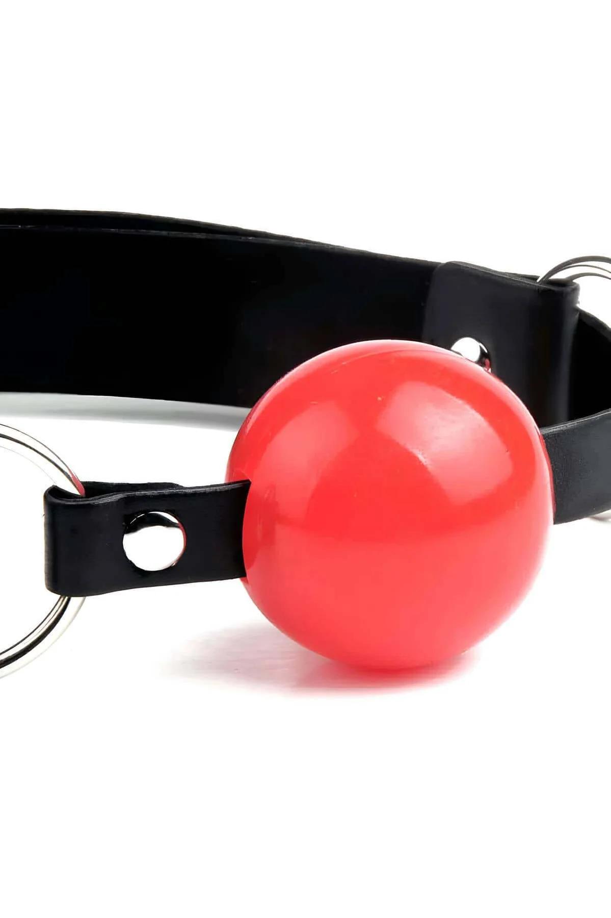 close-up of glossy red 4 cm plastic ball secured between two silver O-rings on black PU strap