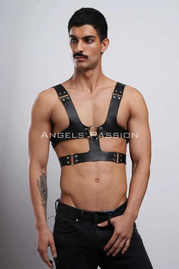Black faux leather chest harness with centered bronze O-ring and adjustable shoulder straps on male model