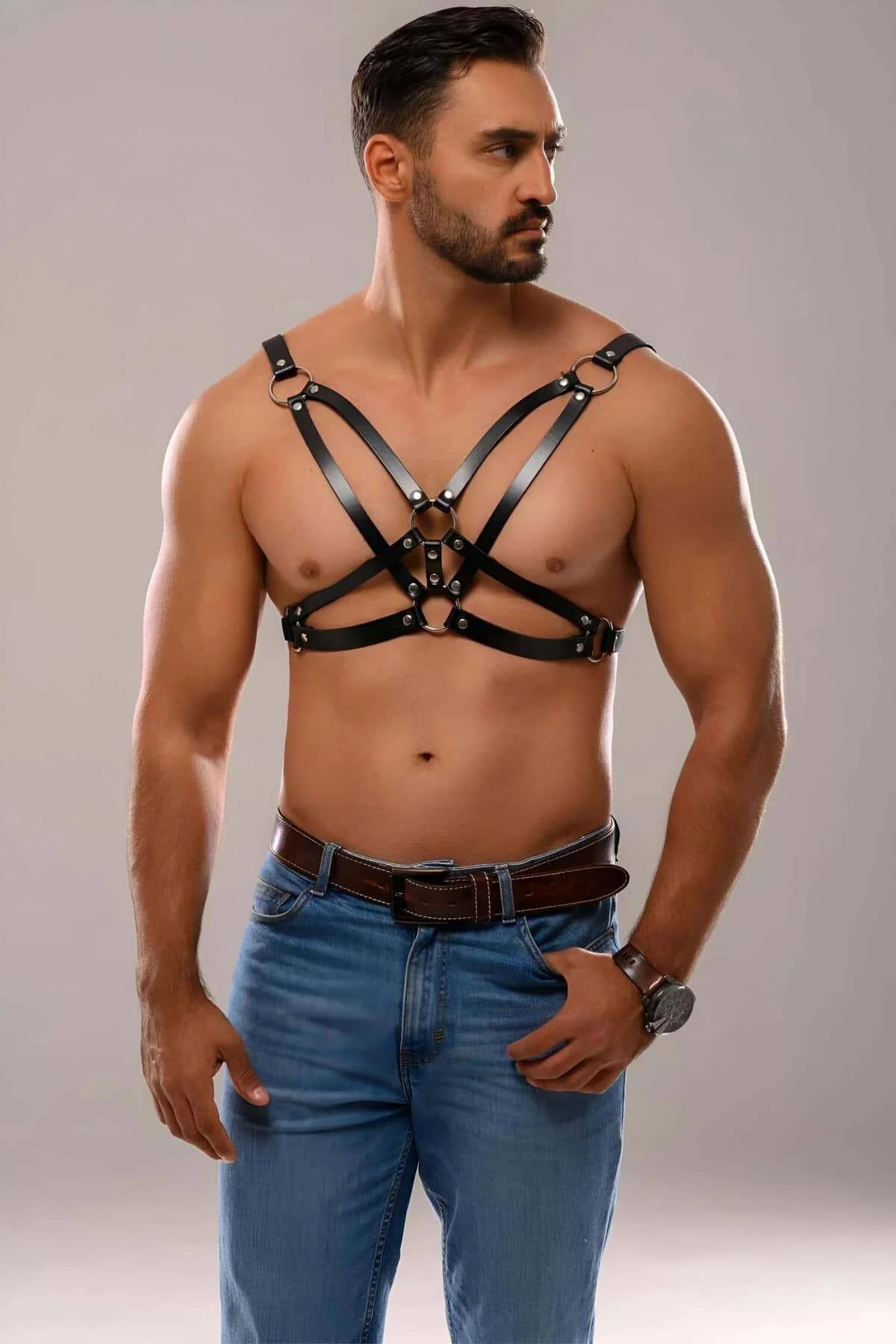 Men's black faux leather harness with four-buckle X-back strap layout on male model with jeans