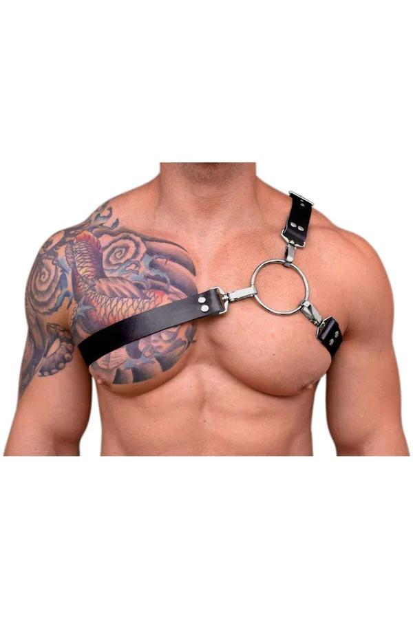 Black faux leather O-ring chest harness with silver clips and rivets worn on male torso showing asymmetric one-shoulder strap