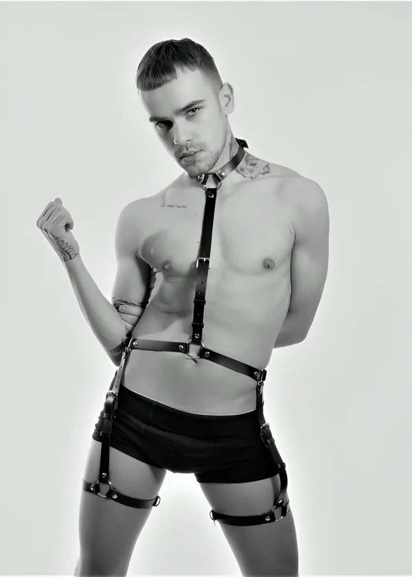 Black faux leather full body harness with collar, chest strap, waist band, and thigh garter loops on male model