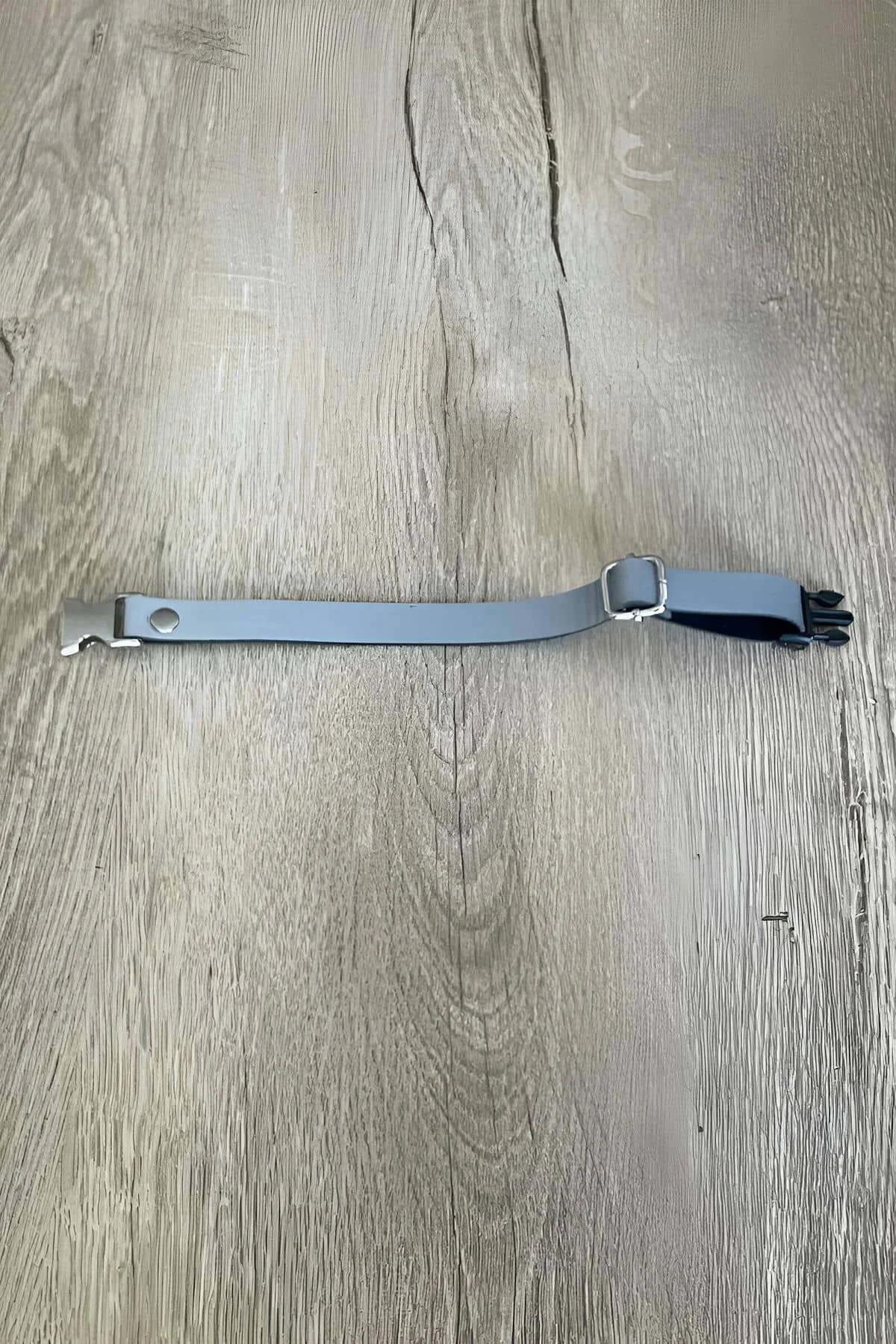 Close-up of silver snap buckle on grey vegan leather choker showing press-button quick-release mechanism