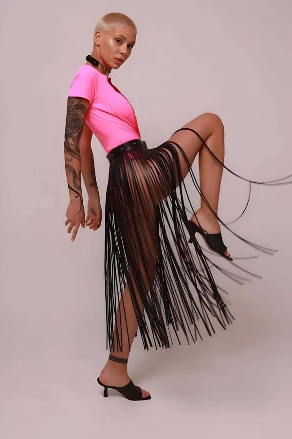 black faux leather fringe skirt overlay with studded waistband worn over pink bodysuit midi length