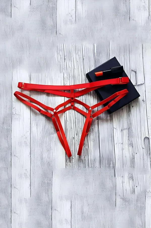 Red strappy thong harness with three elastic waist bands and gold-tone adjustable slider buckles on white wood surface
