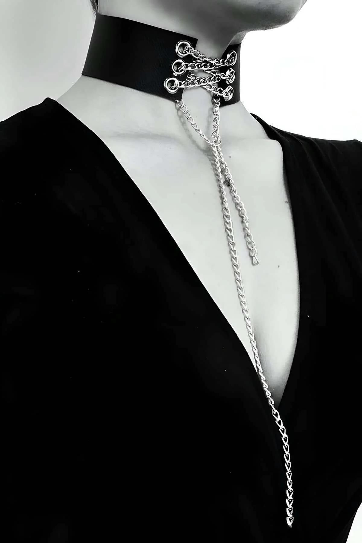 Black faux leather choker with three silver O-rings and multiple curb-link chains draped down the chest