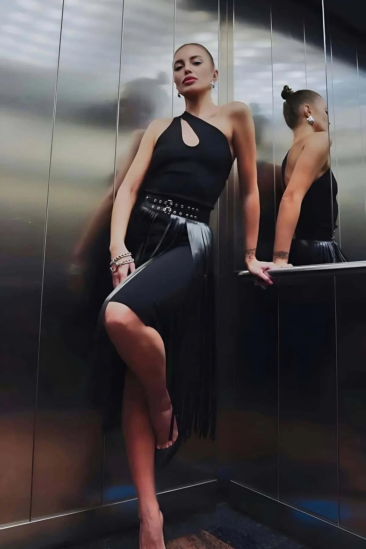 Black faux leather tasseled midi skirt with wide silver eyelet studded belt, pencil fit, fringe hem