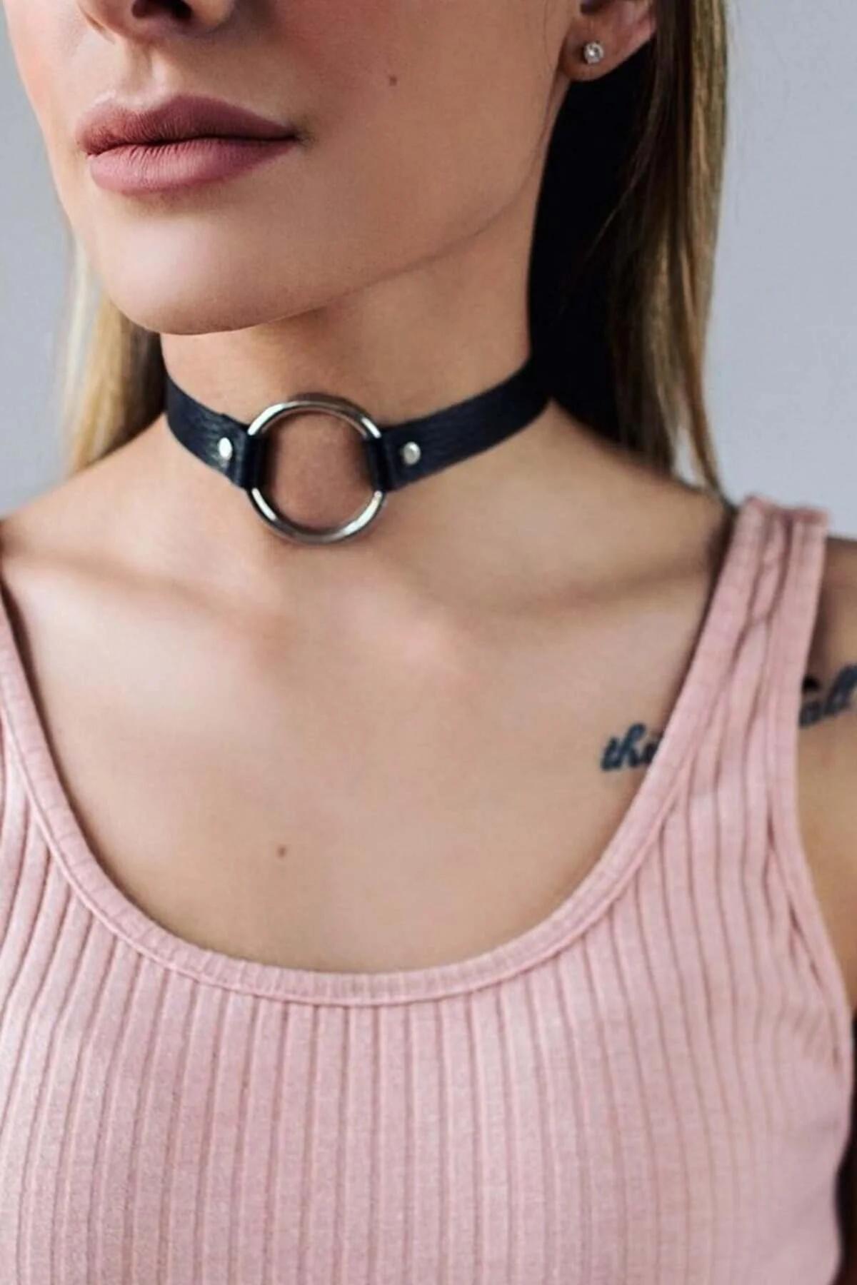 Black faux leather choker with single large silver O-ring centered on flat 1.5 cm band, worn at throat